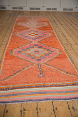 Distressed vintage Kurd runner displaying tangerine, pink, and purple geometric medallions.