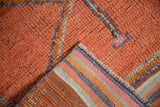 Distressed Kurd rug's abrashed tangerine-rust pile, revealing striped pink, purple, and silver reverse.