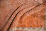 Distressed hand-knotted texture in tangerine orange, dusty rust, and ivory border section.