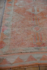 Distressed Kurd runner's textured pile, featuring geometric triangle border in tangerine and faded beige.