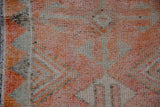 Distressed pile texture of the Kurd rug in tangerine orange and faded silver geometric patterns.