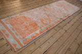 Distressed tangerine orange pile showing geometric triangle border on vintage Kurd runner.