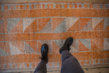 Distressed vintage Kurd rug, showing varied tangerine orange tones and geometric diamond patterns.