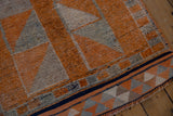 Distressed vintage Kurd runner detail: tangerine orange, gray diamond patterns, textured pile, geometric border.