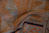 Distressed tangerine orange and silver pile of the vintage Kurd runner, exposing its navy blue patterned flat-woven back.