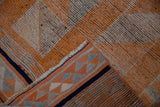 Distressed vintage Kurd runner corner, showing orange-beige pile, navy selvage, woven reverse.