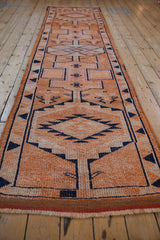 Angled view down the length of a distressed Kurd runner with orange and navy geometric medallions.