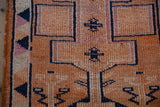 Evenly worn pile of a vintage Kurd rug showing tangerine orange and navy blue geometric motifs.