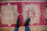 Textured fuchsia and beige geometric Kurd runner with visible knot heads.