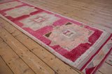 Fuchsia and sand geometric motifs and distressed pile texture of a vintage Kurd rug edge.