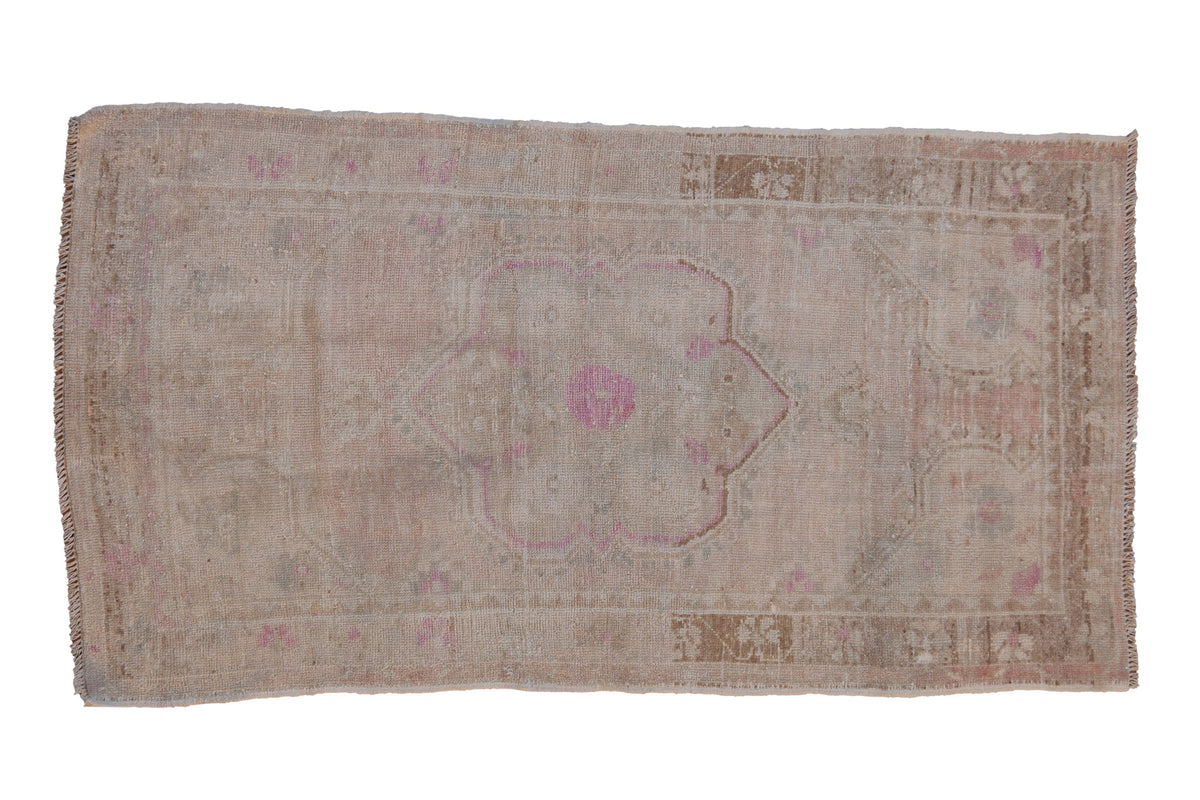 Vintage distressed Oushak rug with a scalloped medallion in dusty rose on a pale, sand-colored field.