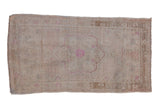 Vintage distressed Oushak rug with a scalloped medallion in dusty rose on a pale, sand-colored field.