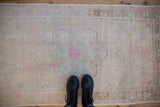 Even wear across the low pile of a distressed Oushak rug with soft rose tones.
