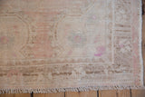 Evenly worn pile of a vintage Oushak rug showing exposed knot heads and short fringe.
