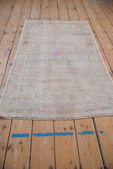 High-angle view of a distressed Turkish Oushak rug showing its low-pile texture and soft, faded rose tones.