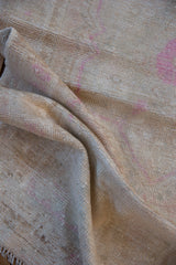 A soft fold in the distressed Oushak rug highlights its even wear and low-pile texture.