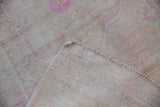 Back view of a distressed Oushak rug, detailing the hand-knotted foundation and side cord selvage.