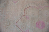 Evenly worn texture of a distressed Turkish Oushak rug with visible knot heads and pink accents.