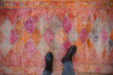 Overhead view of a vintage Kurd runner's distressed texture and colorful diamond-patterned pile.