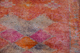 Close-up of the hand-knotted wool pile showing tangerine, fuchsia, and silver diamond motifs.