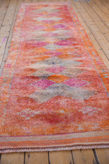 Distressed Kurd rug runner viewed down its length, highlighting its colorful diamond design.