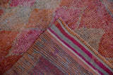 Folded corner of a distressed Kurd rug showing the striped foundation and colorful short pile.