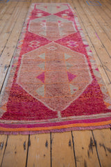 Distressed pile texture of a Kurd runner, showing raspberry red triangles, fuchsia tones, and orange fringe.