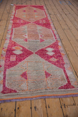 Distressed Kurd runner close-up: primitive geometric patterns in fuchsia, orange, and ivory with fringe.