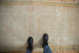 Soft, distressed pile of a vintage Oushak runner with pale pink, seafoam green, and dusty gold tones.