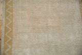 Close-up of the distressed Turkish Oushak's low pile and meandering chevron vine border.