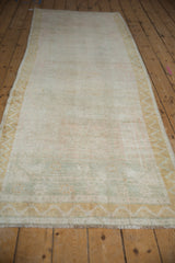 The soft, faded texture of a vintage Turkish Oushak runner viewed down its length.