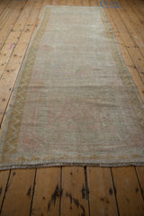 Low perspective view of a distressed Oushak runner showing its soft, even wear and length.