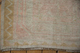 A vintage distressed Oushak runner's corner with a gold chevron border and soft, worn pile.