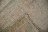 A folded corner of the Oushak runner shows its distressed pile and sturdy hand-knotted back.