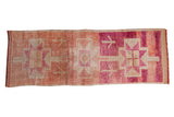 Distressed Kurd runner rug with primitive geometric starbursts in fuchsia, ruby, and beige tones.