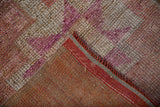 Woven foundation and secured edge of a vintage Kurd runner, showing distressed fuchsia and beige pile.