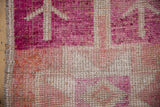 Close-up of distressed Kurd rug, showing primitive patterns in fuchsia, rose, beige, and abrash.