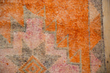 Distressed vintage Kurd rug texture with vibrant tangerine, pale fuchsia, and muted tones.