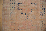 Visible side selvage and distressed hand-knotted pile with faint foundation, ivory, blush, and cobalt accents.