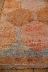 Textured pile and distressed orange, blue, and pink panels of a vintage Kurd runner.
