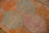 Distressed vintage Kurd runner with textured orange, slate blue, and faded pink lattice panels.