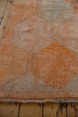 Distressed texture and faded dusty tangerine orange geometric panels on a vintage Kurd runner.