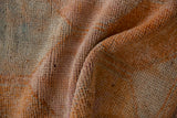 Close-up of distressed vintage Kurd rug pile, featuring dusty tangerine and slate blue.