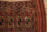 Geometric guls in madder red and navy, with a striped flatweave kilim end on the antique rug.