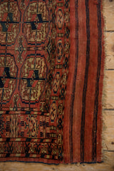 Antique Turkmen rug's unique piled end finish, featuring navy stripes on madder red.