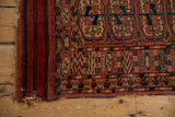 Detail of the antique Turkmen rug's distinctive knotted red end finishing and geometric motifs.