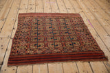 Madder red and navy elephant's footprint guls on an antique Turkmen rug with piled end.