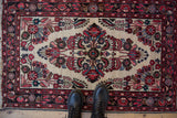 Corner of a vintage Dargezine rug, ivory field, with crimson and navy floral spandrel design.