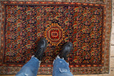 Vintage Persian Serbend rug corner with navy Herati field and tomato red boteh border.
