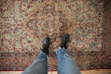Antique Kerman rug's scalloped medallion and bursting floral field in red, ivory, and navy.